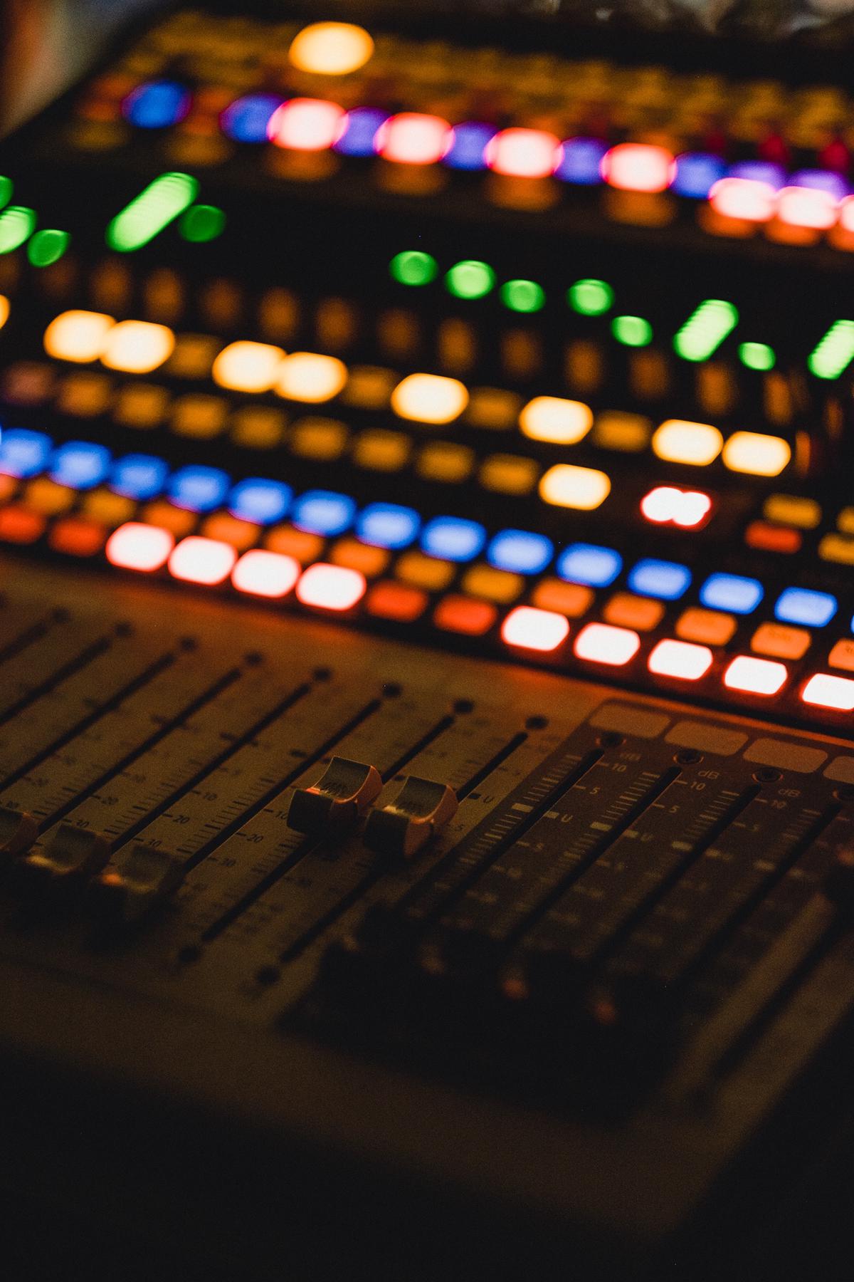 An image of a mixing board with audio waveforms representing the concept of overdubbing in music production.